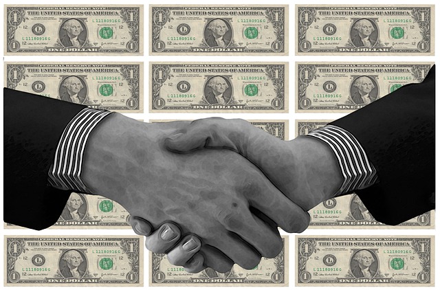 Potřesení rukou dvou podnikatelů a v pozadí jsou bankovky